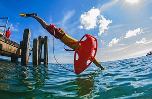 Rettungsschwimmer springt von Steg ins Wasser.