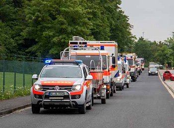 Mehrere DLRG Einsatzfahrzeuge fahren hintereinander auf Kamera zu