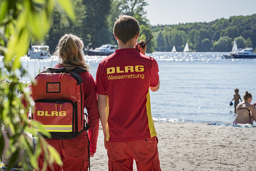 Zwei DLRG-Mitglieder in Einsatzkleidung am Strand.