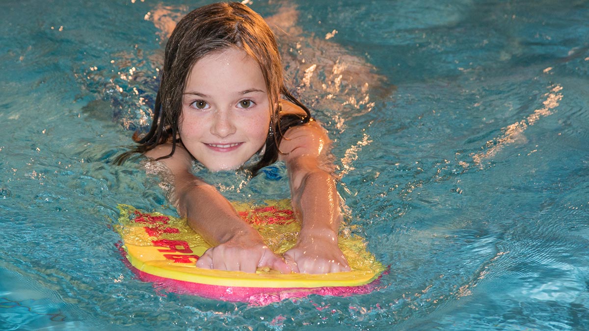 Kind mit Schwimmboard im Becken.